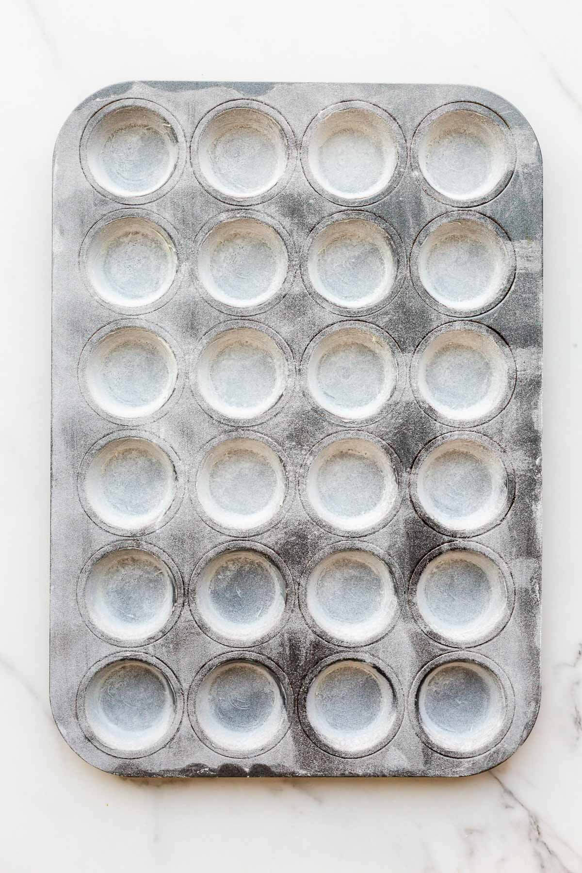 A greased and floured mini muffin pan ready to use for baking cakes and muffins without them sticking to the pan.