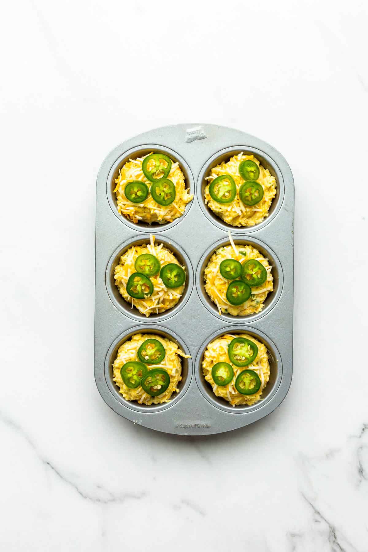 Jalapeño cheddar cornbread muffins before baking in a 6-cup muffin pan.