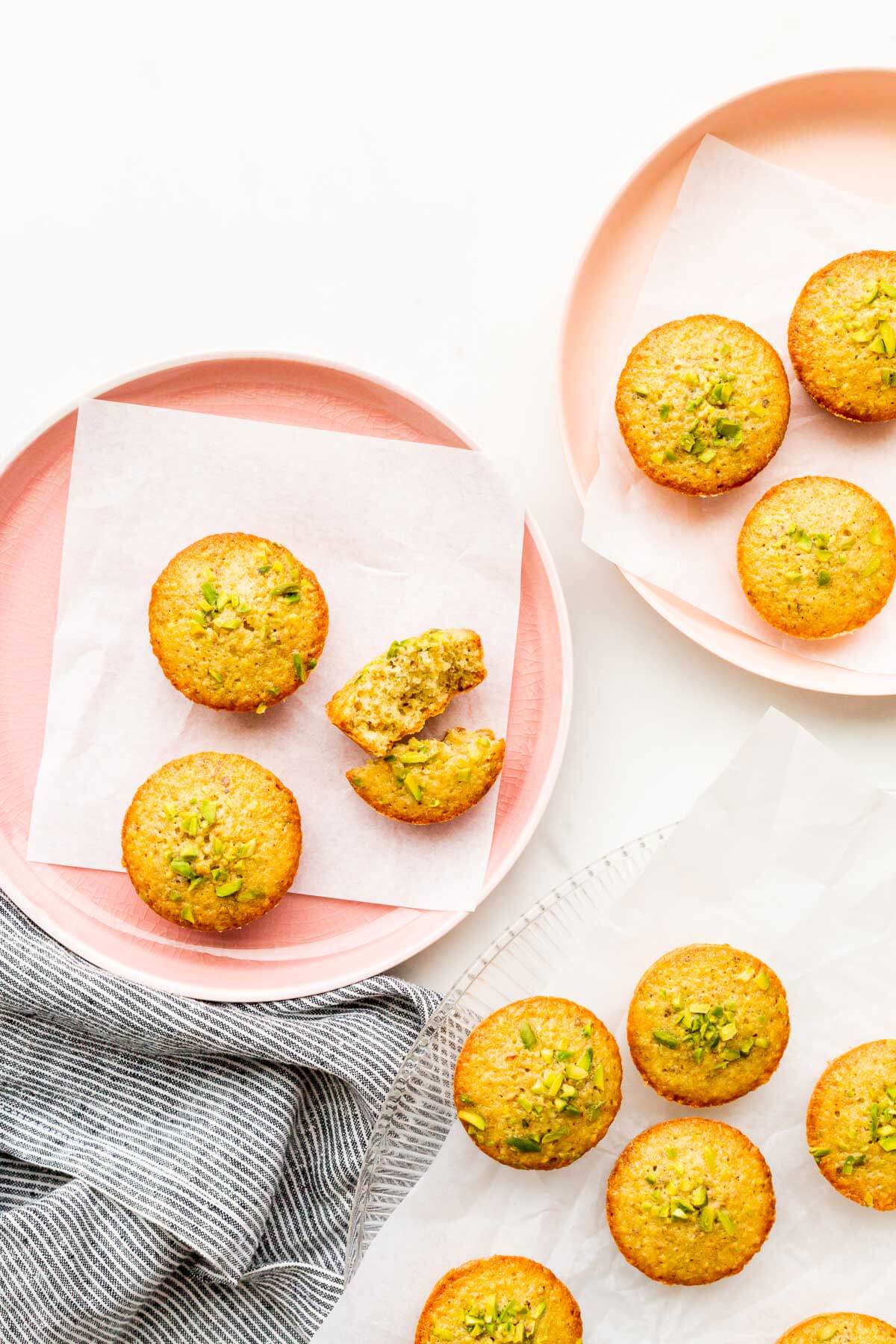 Mini pistachio tea cakes on pink plates, ready to be eaten.