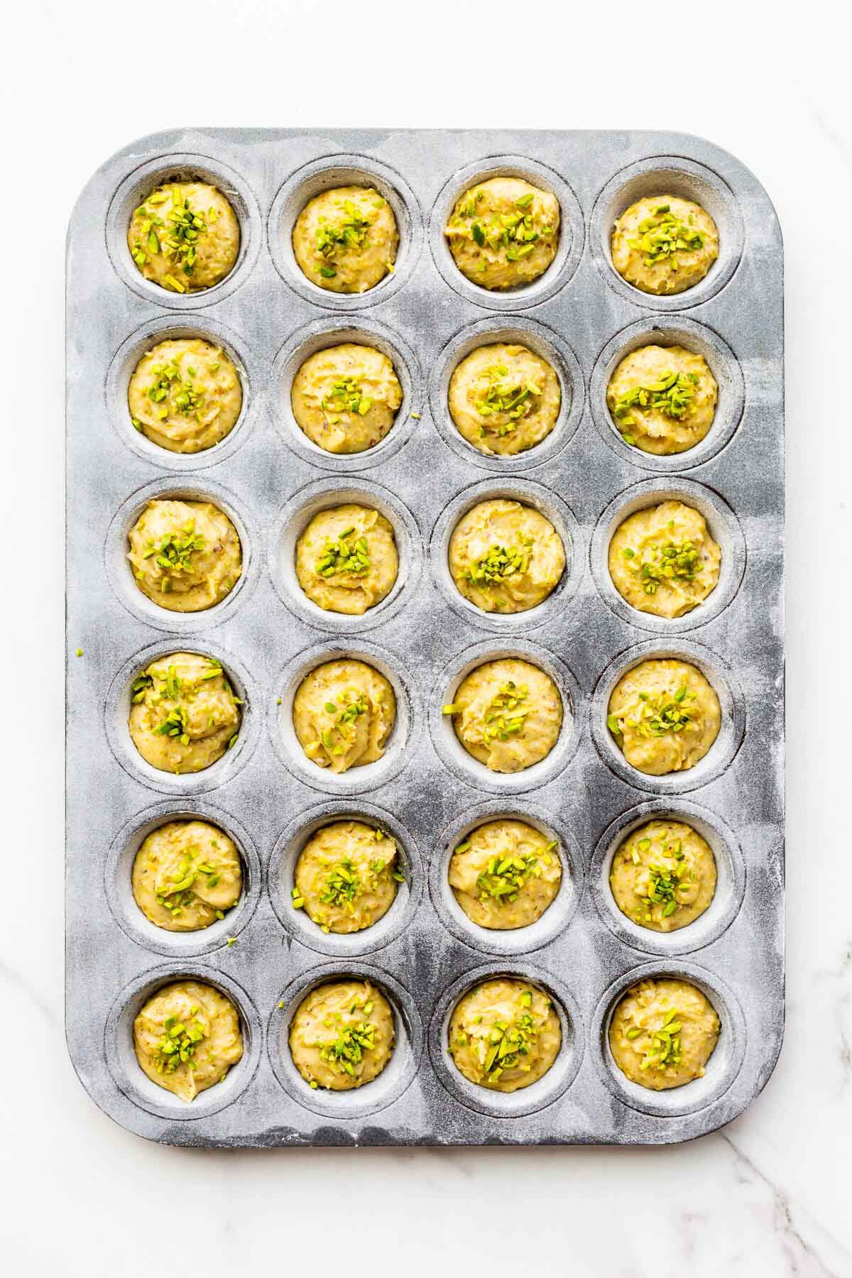 Pistachio financiers before baking in a mini muffin pan.