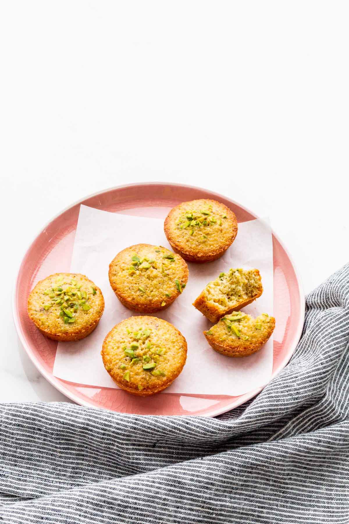 A pink plate with pistachio financiers.