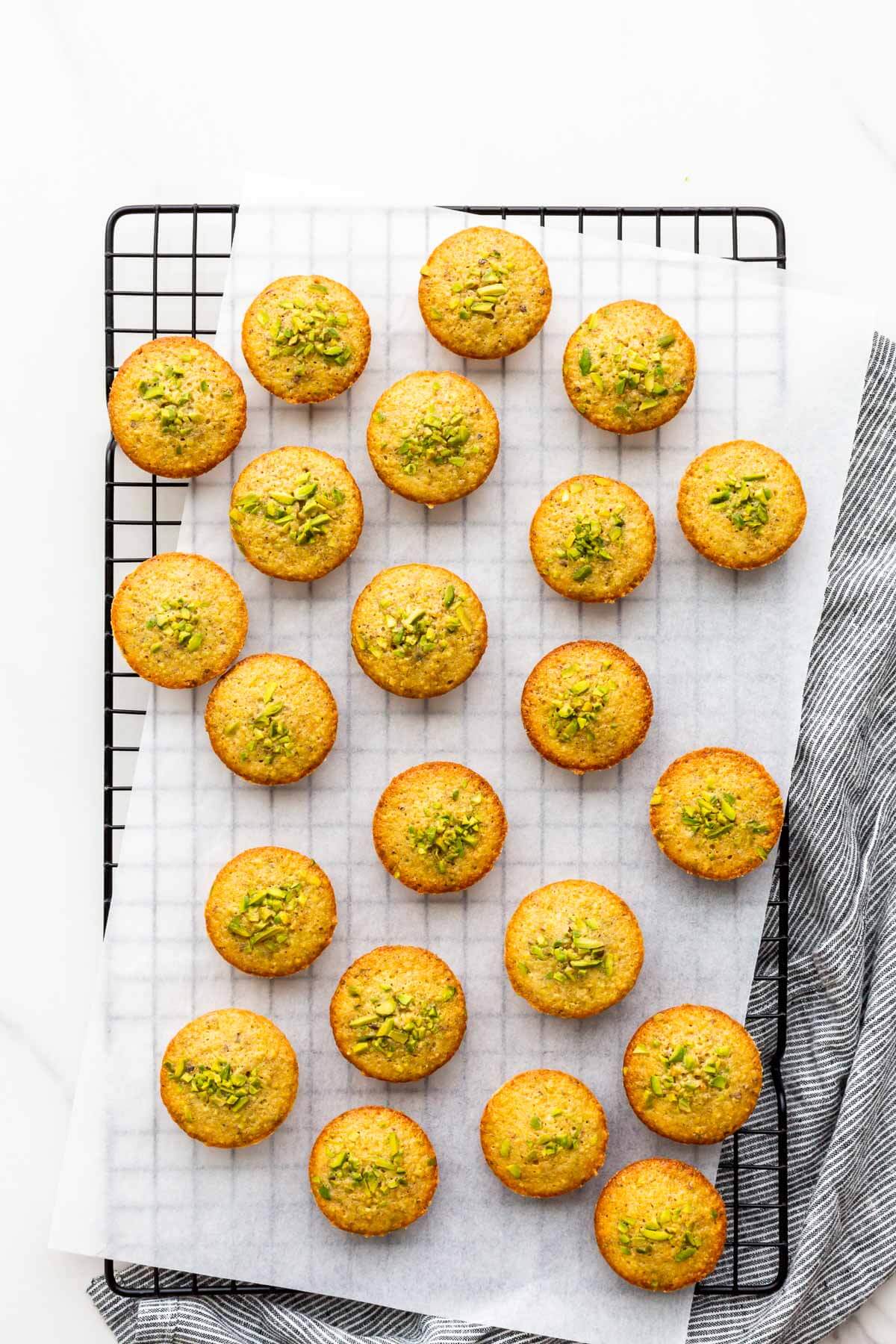 Pistachio financiers on a black cooling rack.