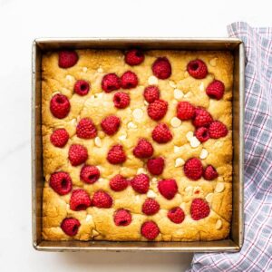 A square pan of raspberry white chocolate blondies freshly baked, ready to be sliced.