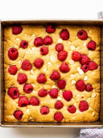 A square pan of raspberry white chocolate blondies freshly baked, ready to be sliced.