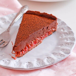 A slice of rhubarb chocolate tart on a blue plate.