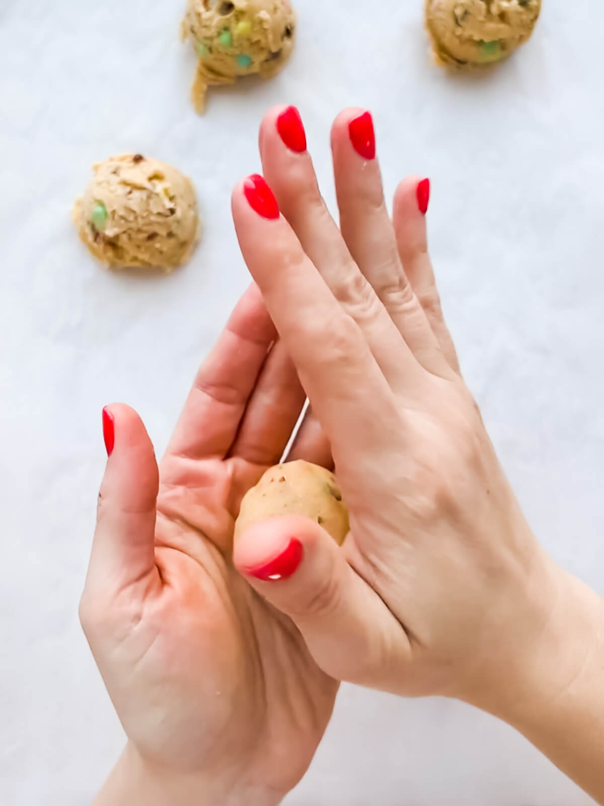 Rolling scoops of cookie dough between the palms of hands to make Easter cookies.