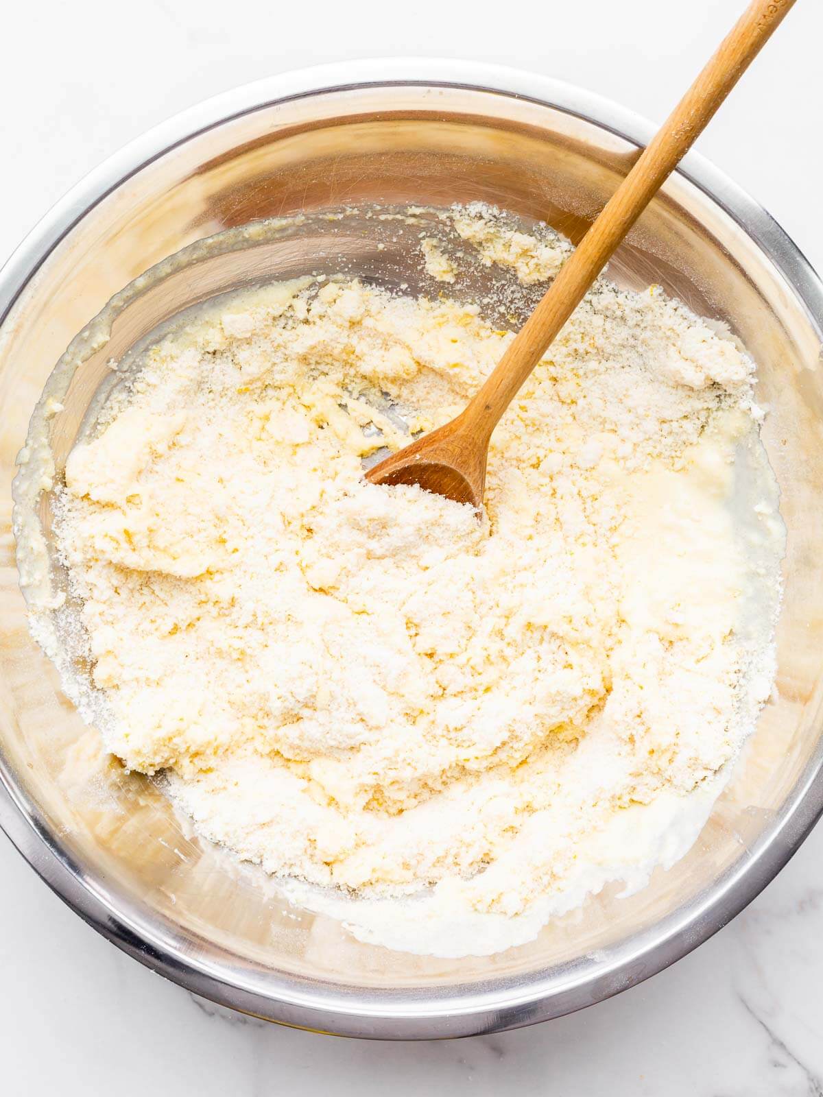 Stirring the wet and dry ingredients together to make a thick muffin batter.