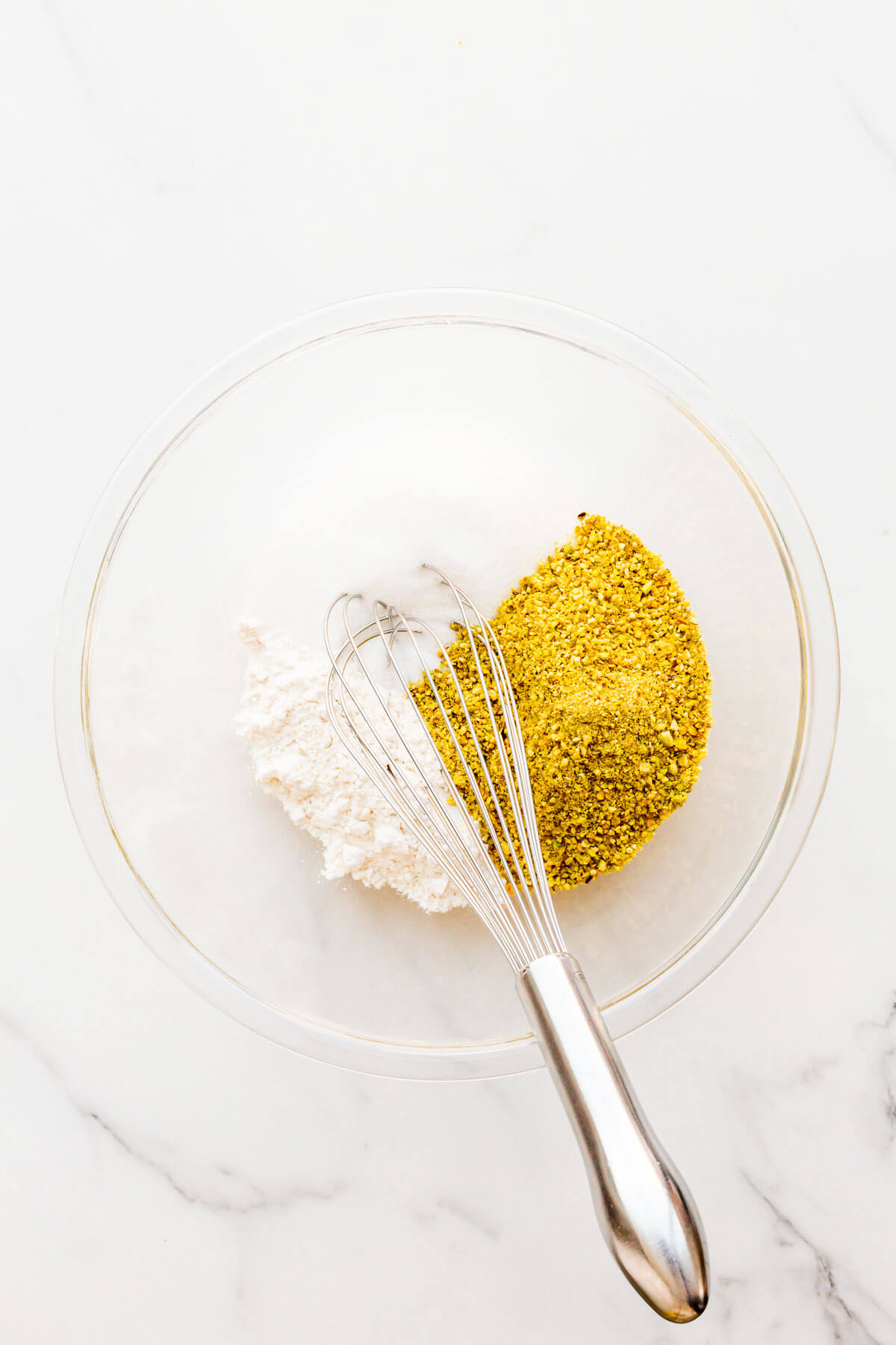 Whisking flour, sugar, and ground pistachio to make financiers.