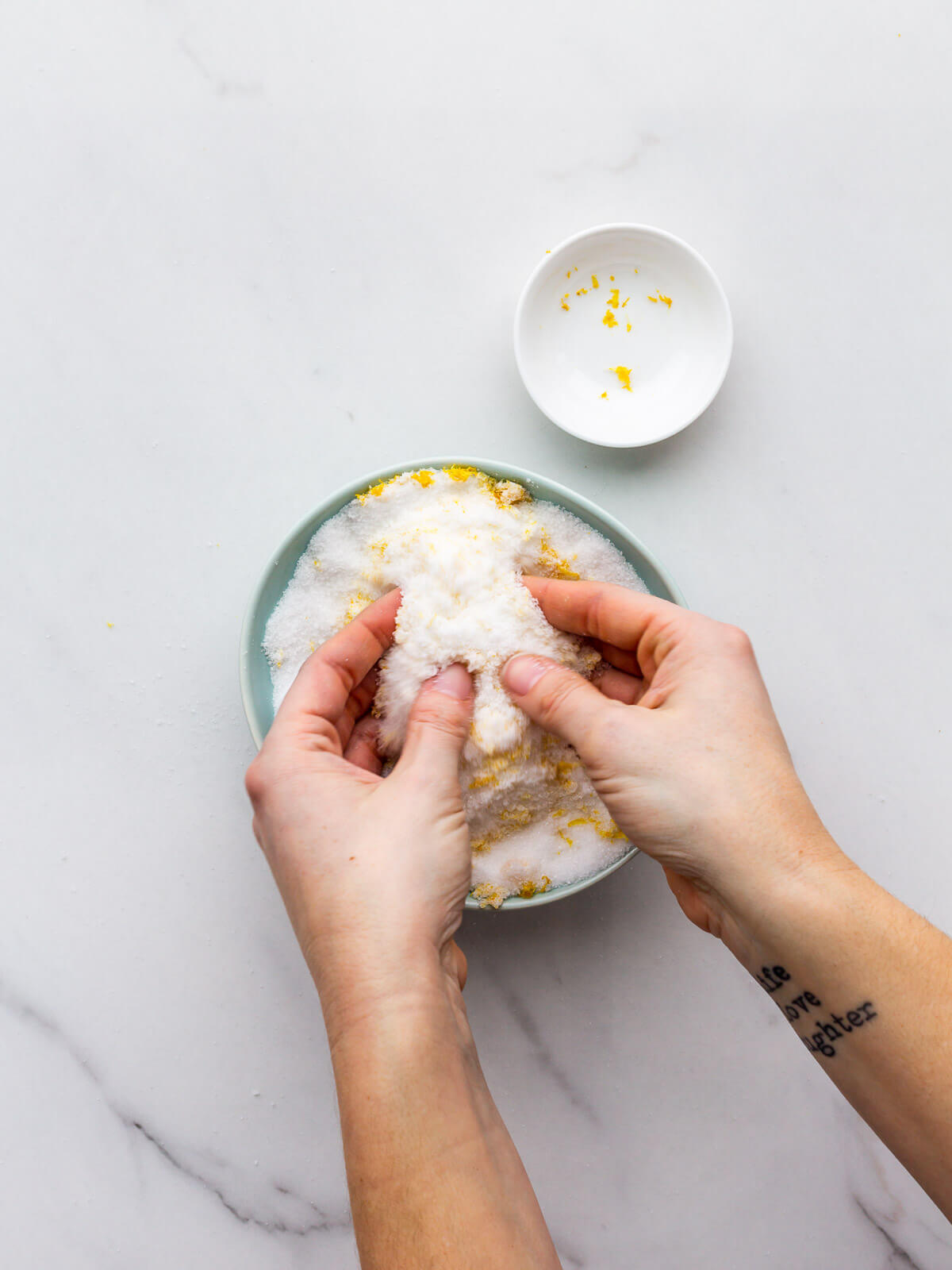 Working lemon zest into sugar to draw out the lemon oil and flavour compounds.