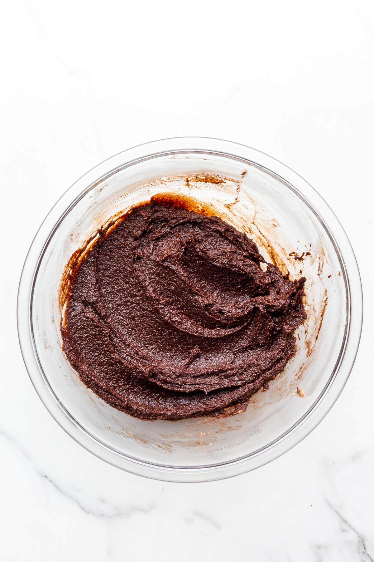 Chocolate batter for financiers in a glass bowl.