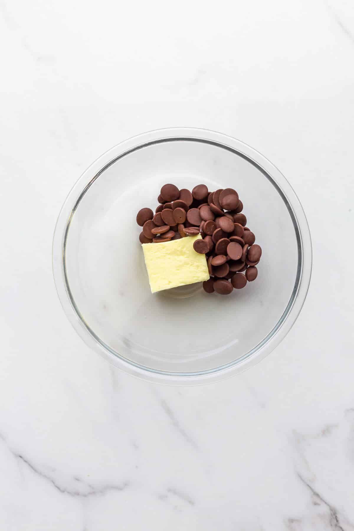 A glass bowl with chocolate and butter to be melted together to make chocolate frosting.