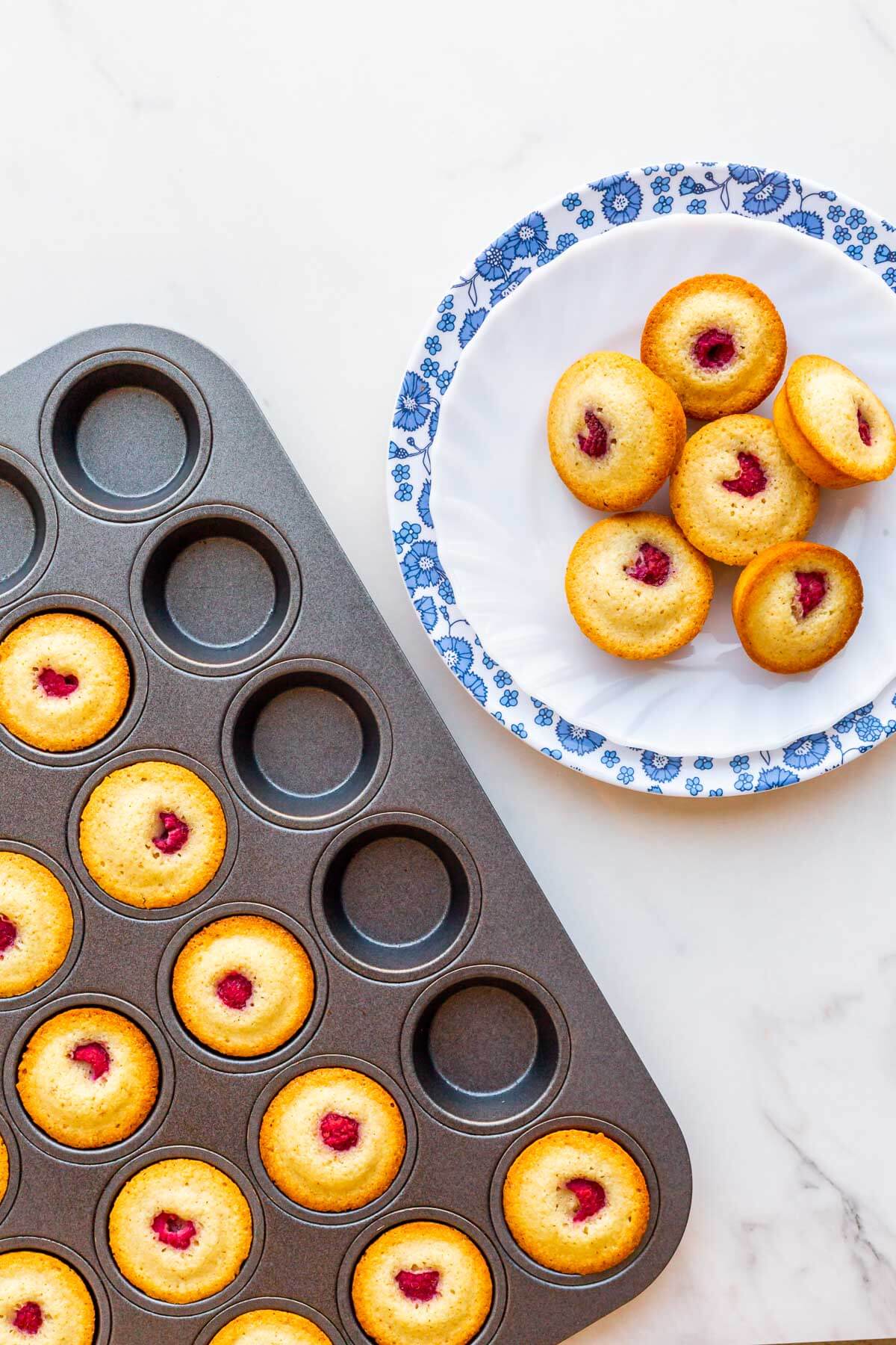 Transferring raspberry almond financiers from a mini muffin pan to a plate after baking.