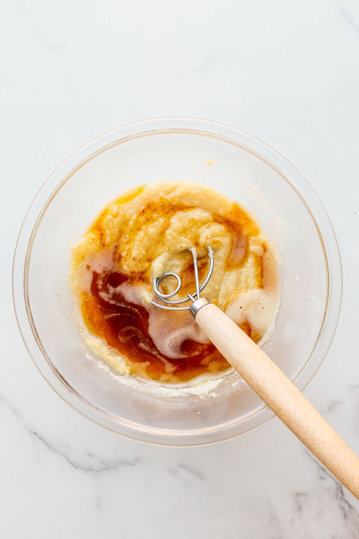 Brown butter added to a glass bowl of cake batter to make almond financiers.