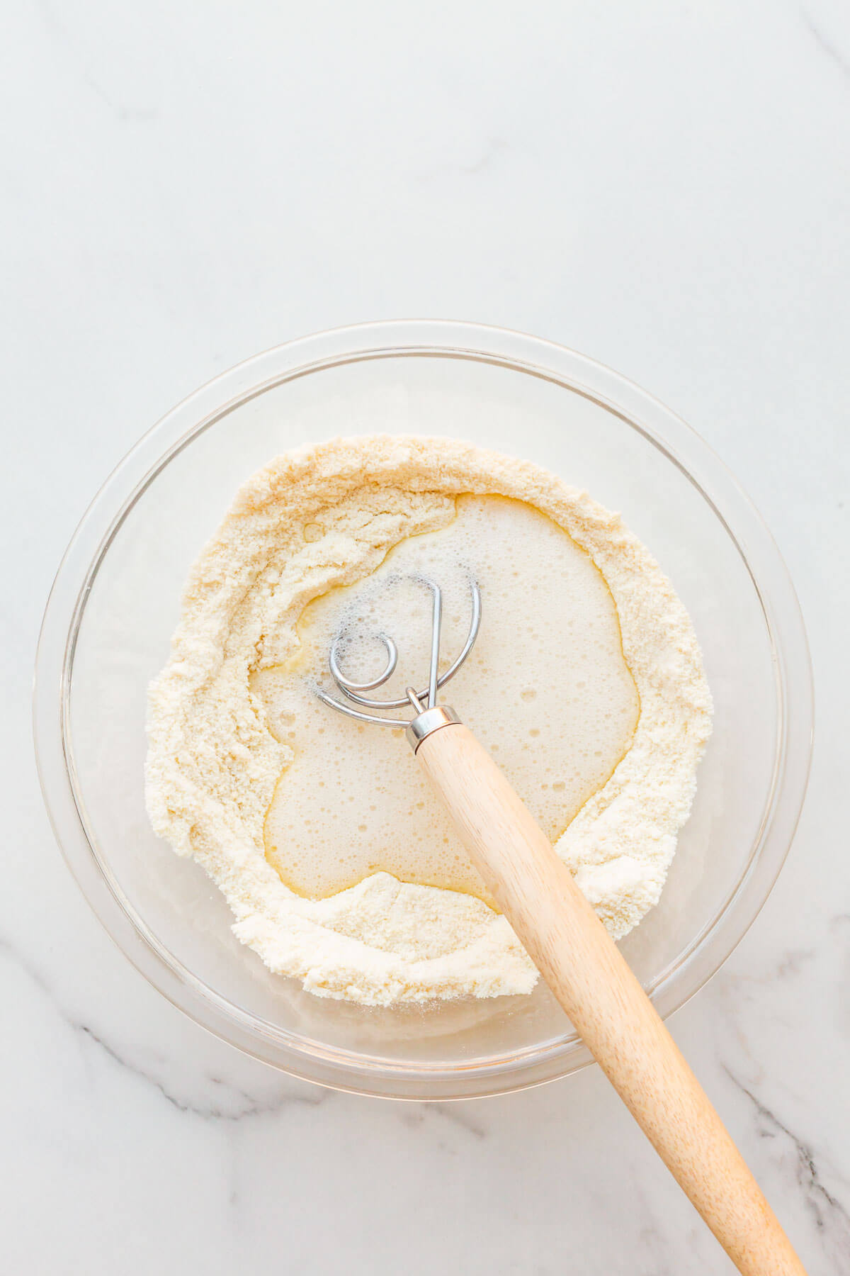 Incorporating frothy egg whites with dry ingredients to make batter for almond financiers.