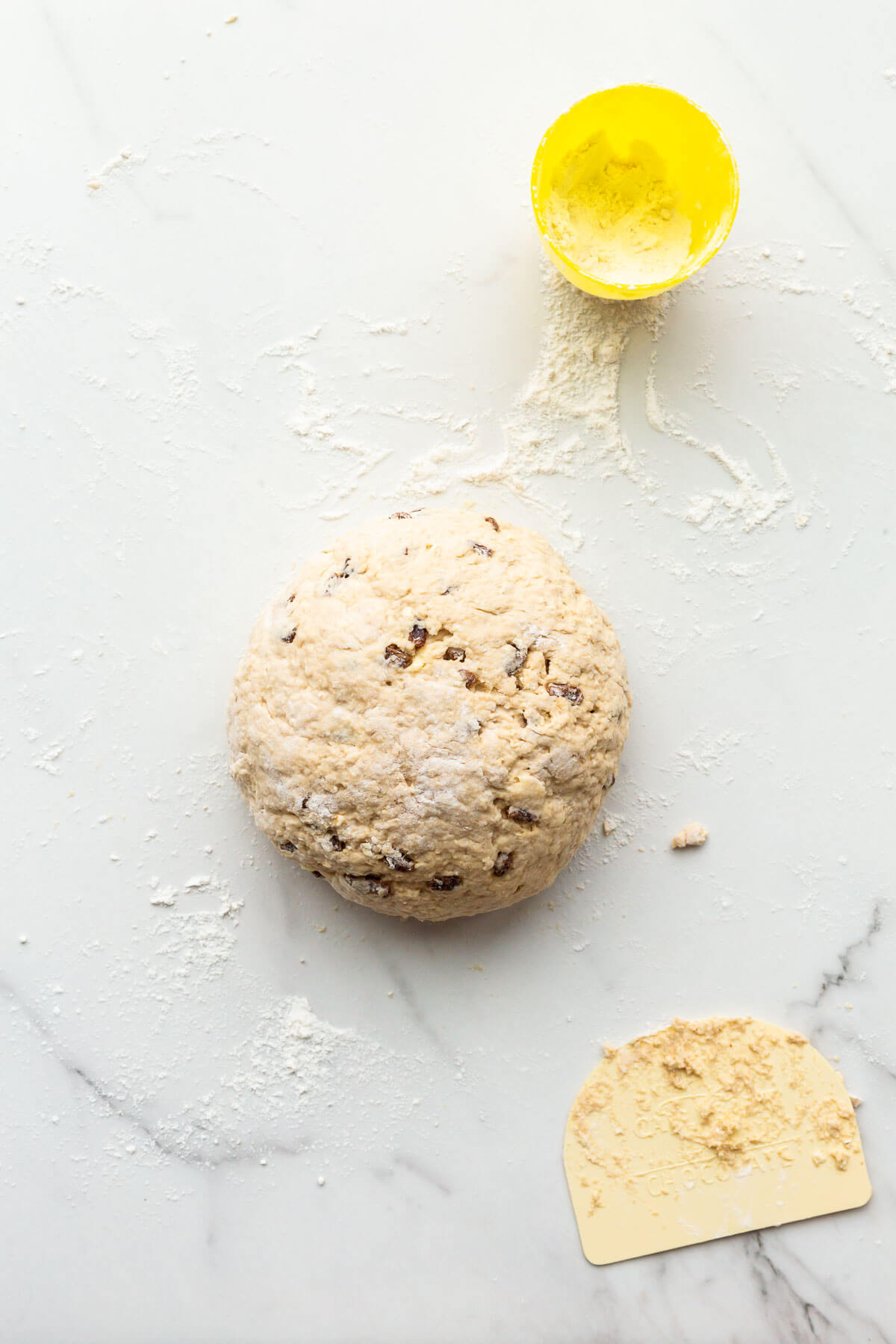 Shaping soda bread on a floured surface with a pastry scraper.