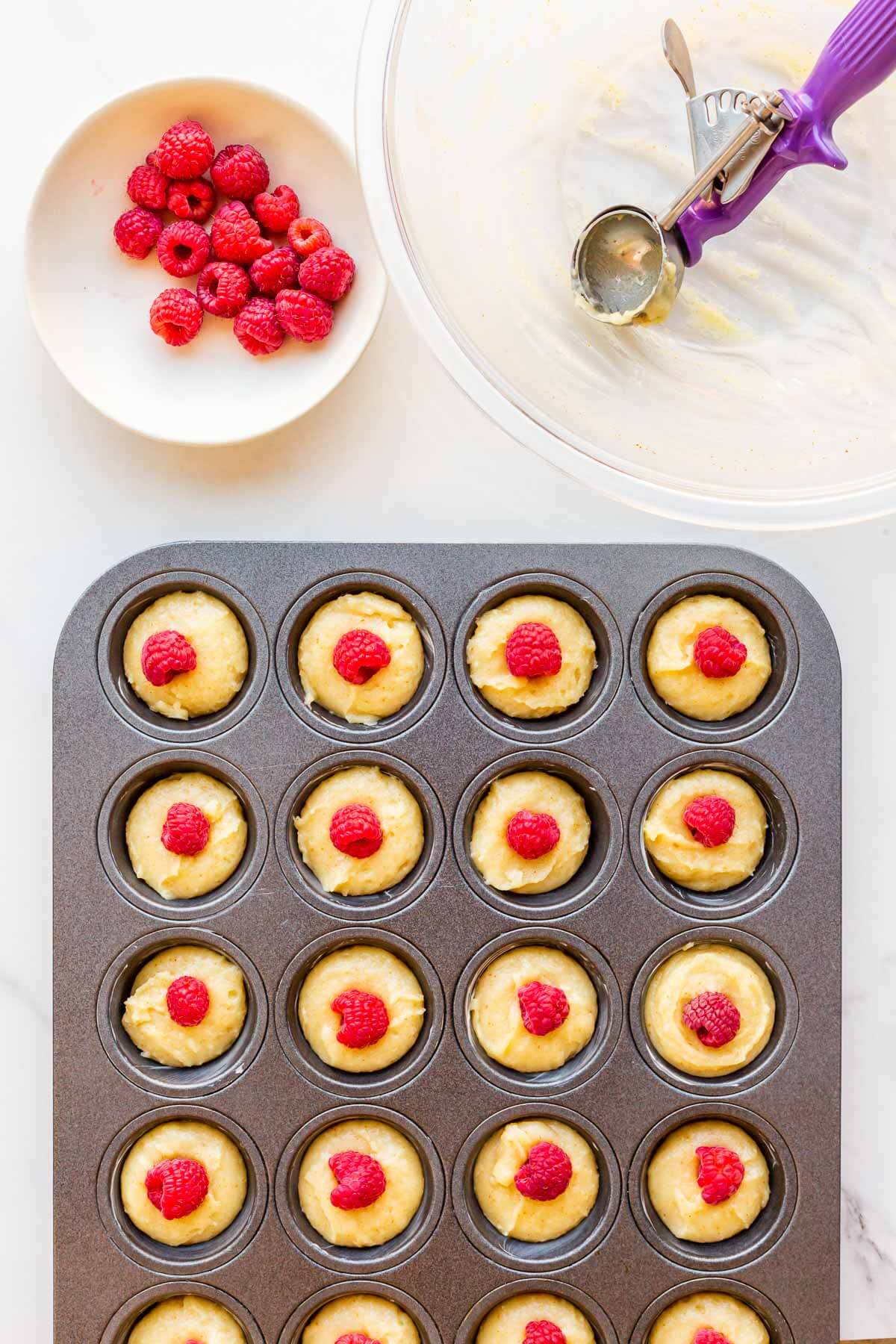 Garnishing almond financiers with fresh raspberries before baking.