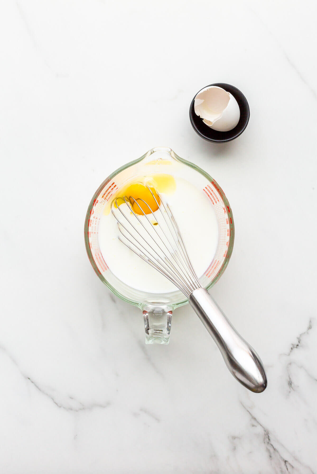 Whisking wet ingredients, including eggs and buttermilk, to make soda bread.