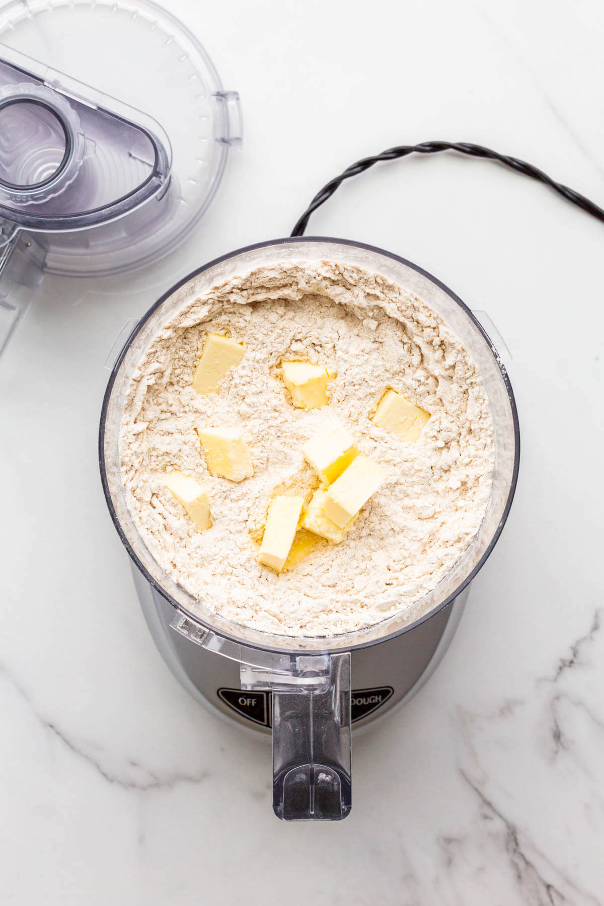 Incorporating butter with dry ingredients in a food processor bowl.