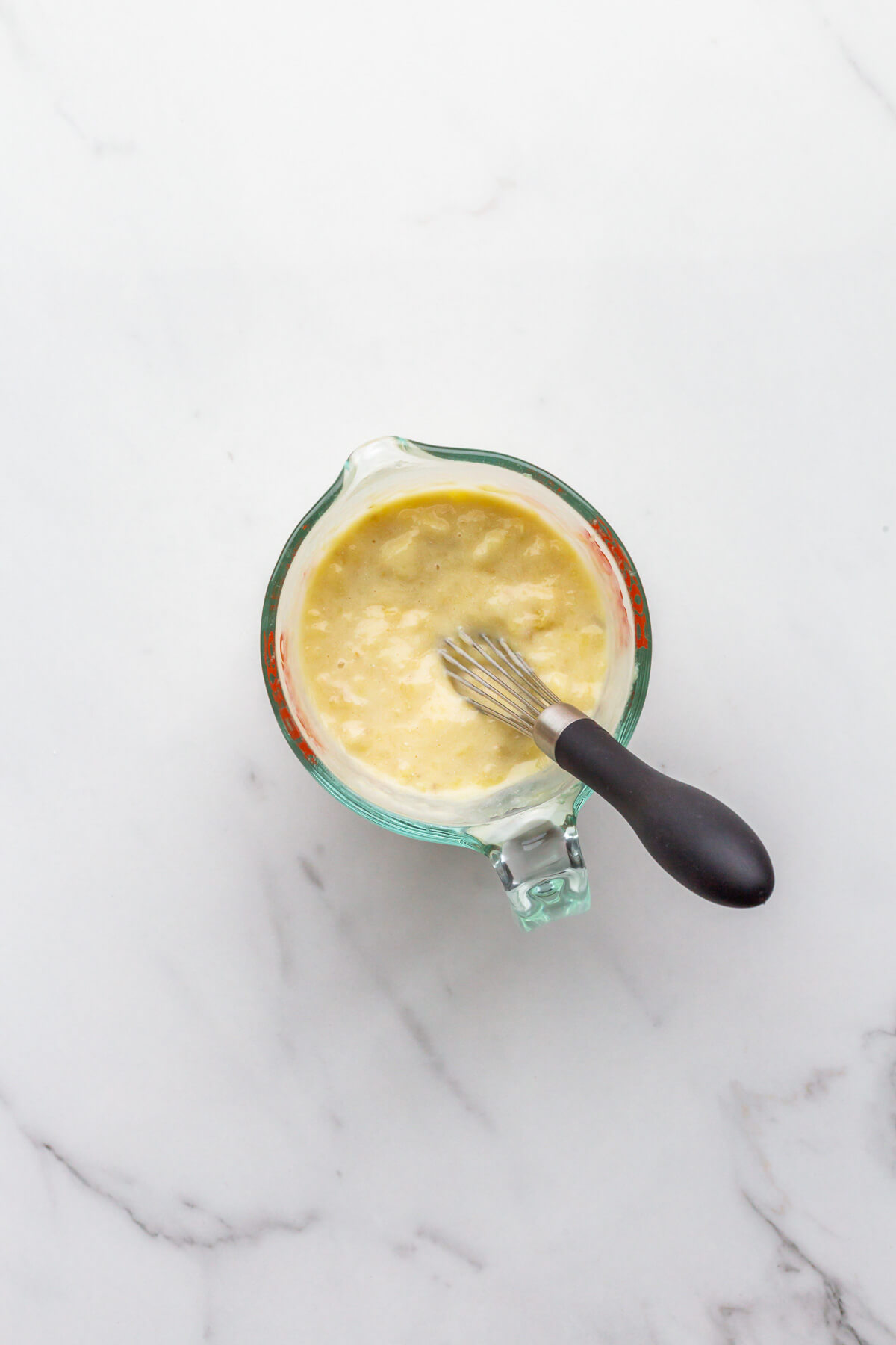 Banana and sour cream whisked together in a spouted measuring cup.