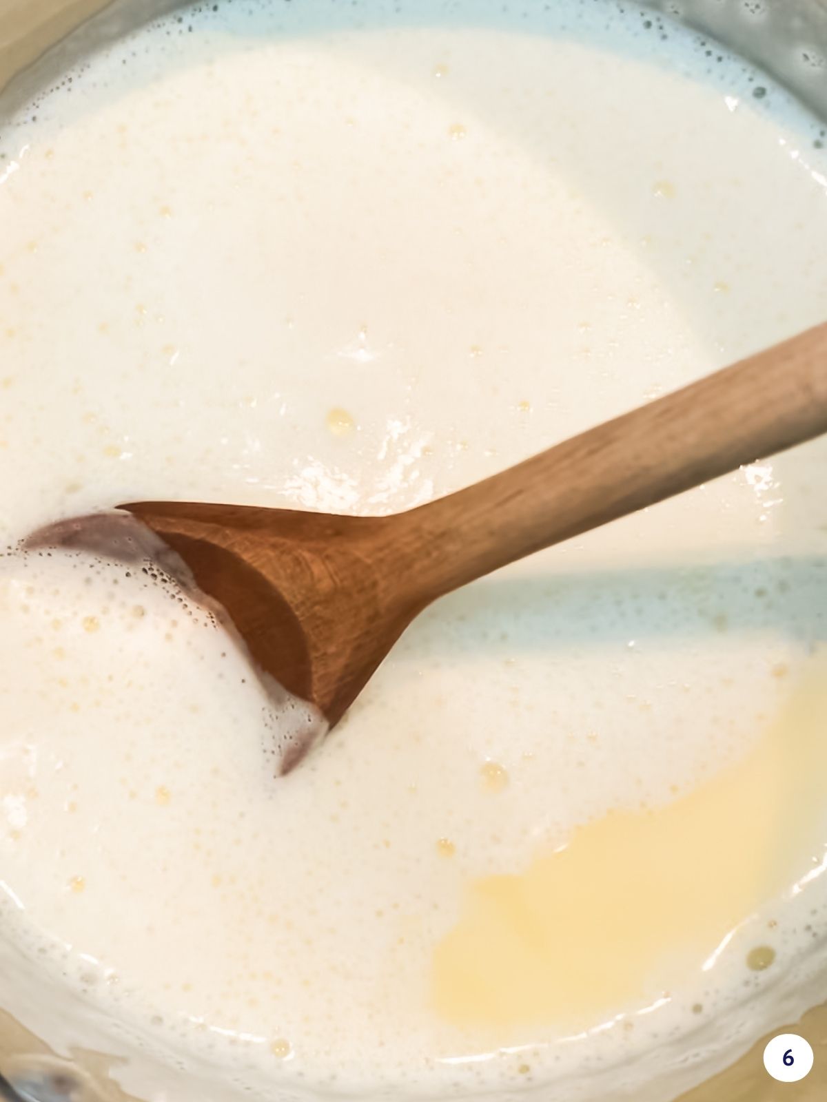 Heating custard sauce on the stove in a saucepan with a wooden spoon to slowly thicken it.
