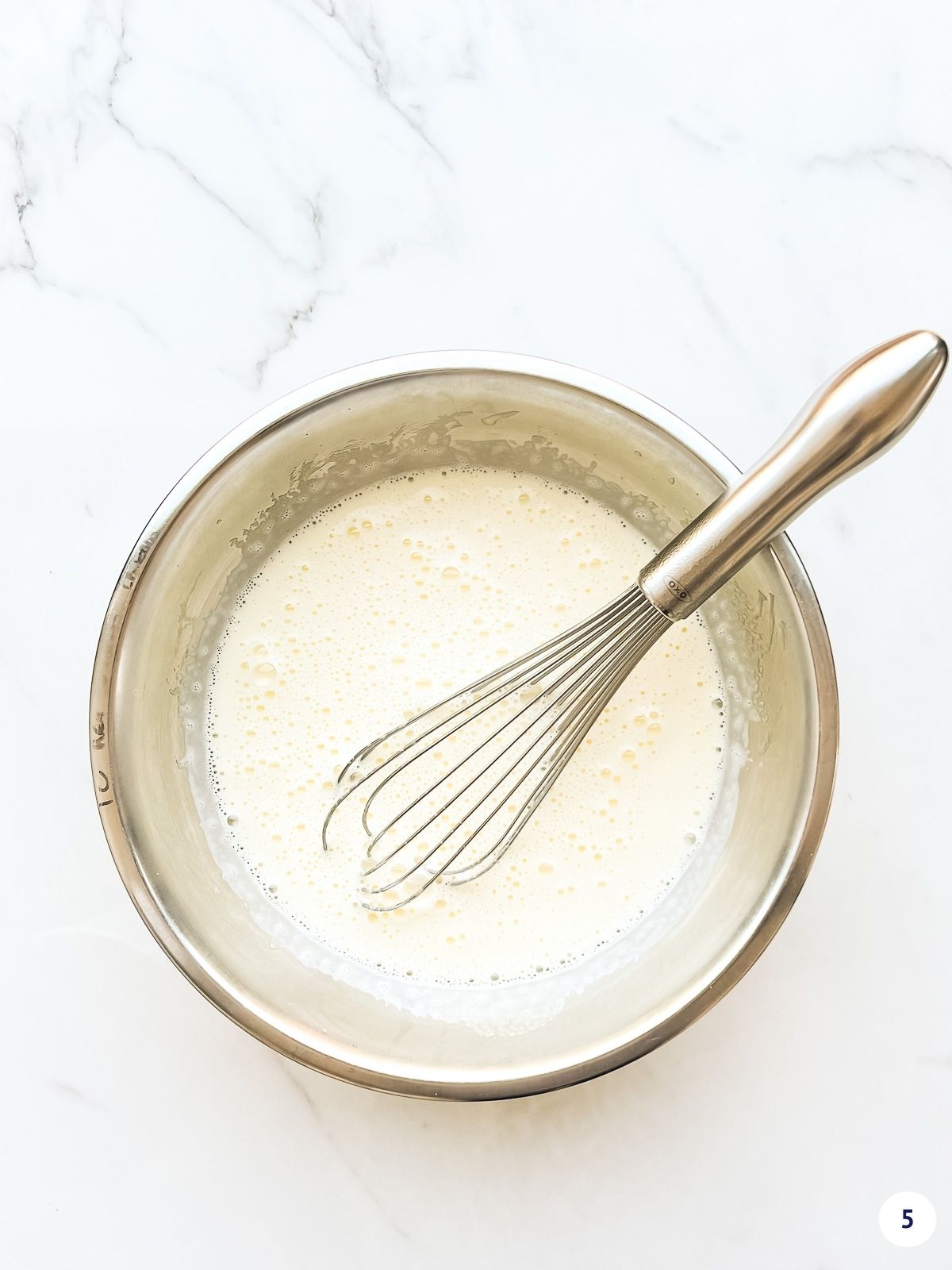 Tempered egg yolks in a metal bowl with a whisk.