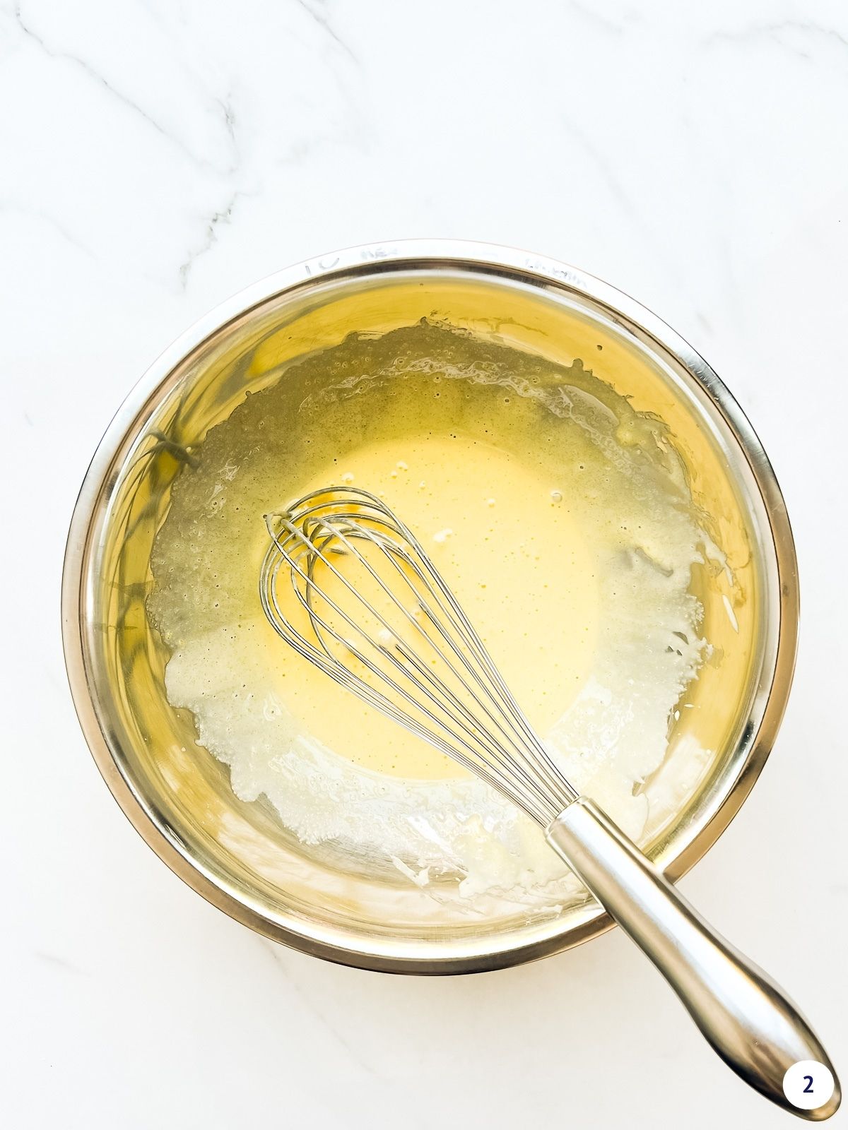 Egg yolks whisked with sugar until very light in colour in a metal bowl with a whisk.