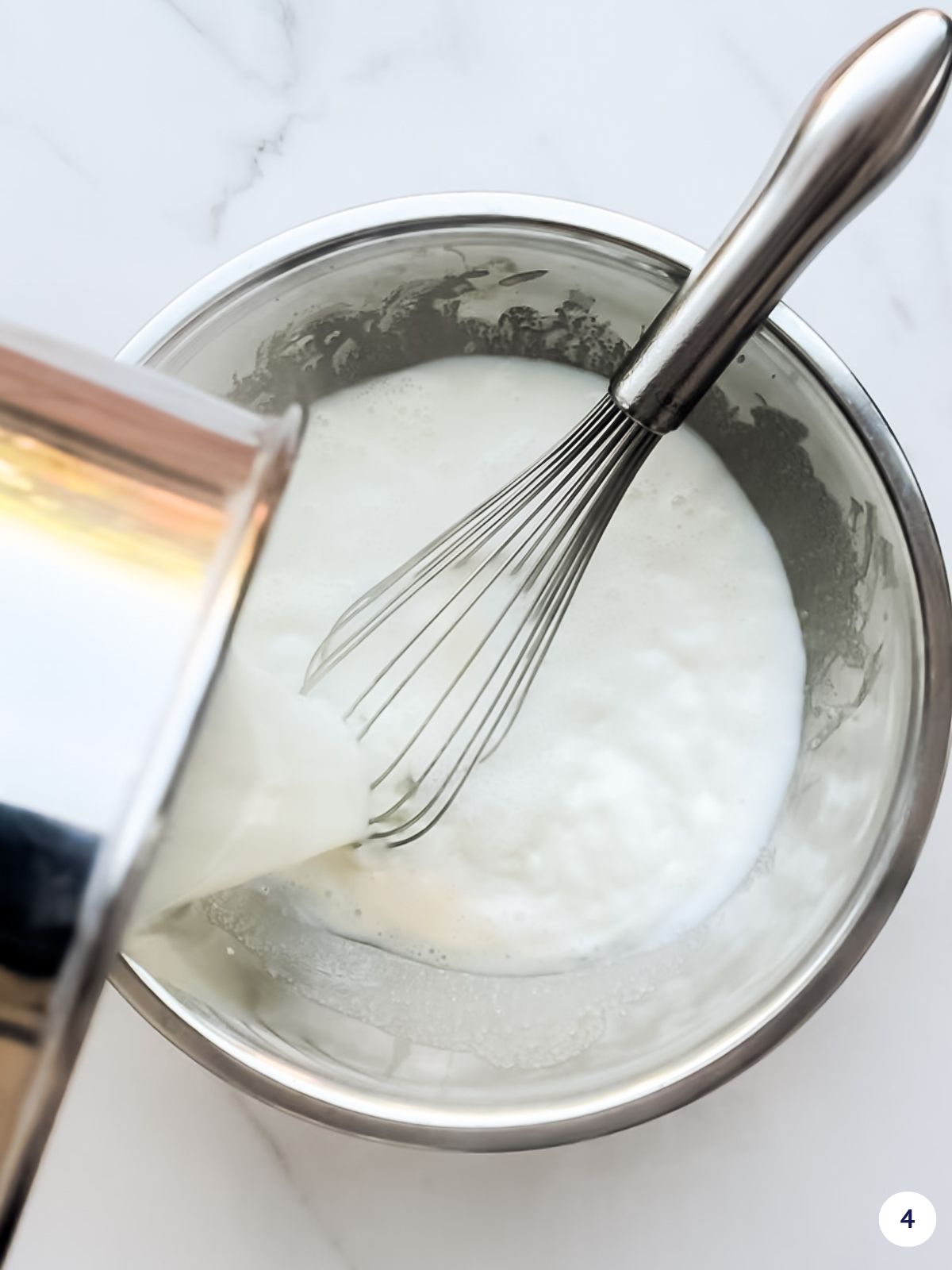 Pouring hot milk over whipped egg yolks and sugar in a bowl to temper the yolks.