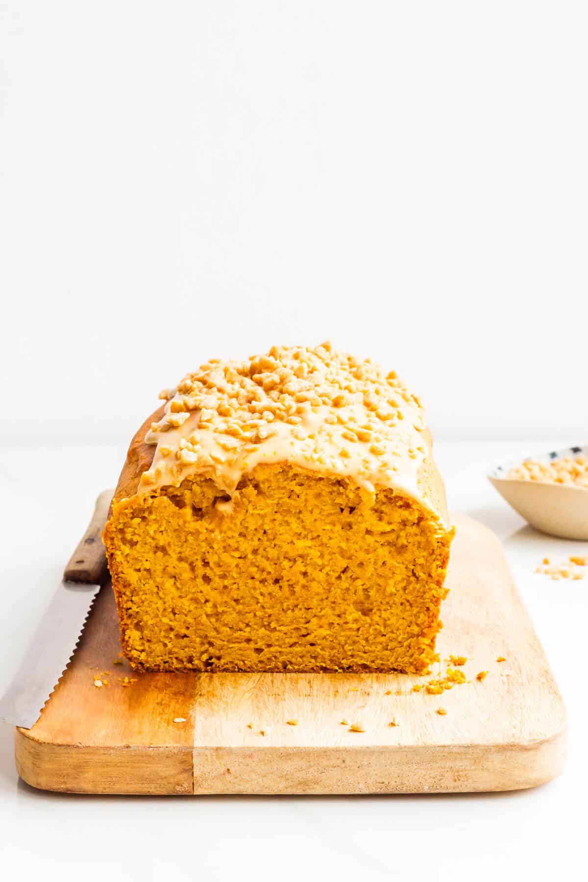 A loaf of maple pumpkin bread sliced on a wood cutting board.