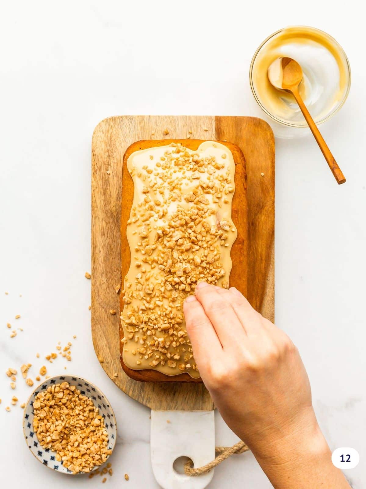 Sprinkling an iced pumpkin bread with maple flakes.