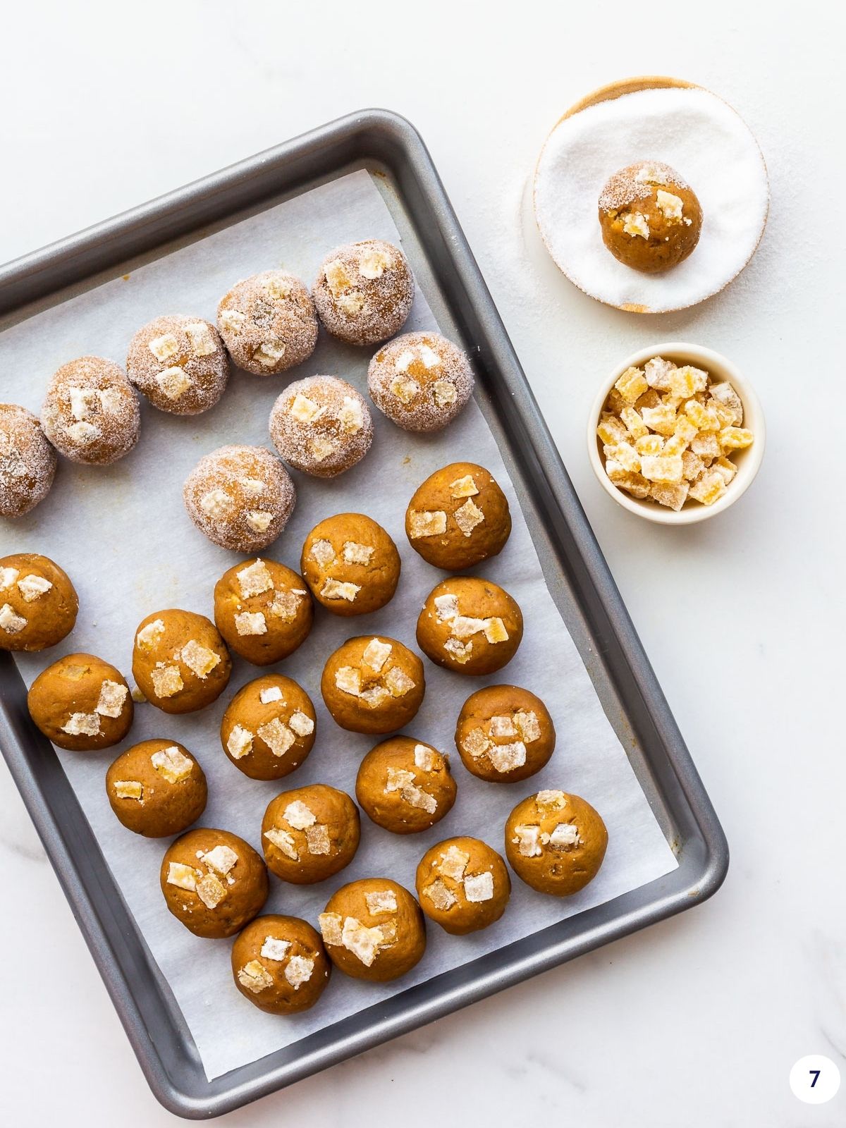 Rolling scoops of ginger cookie dough in granulated sugar to coat them before baking.