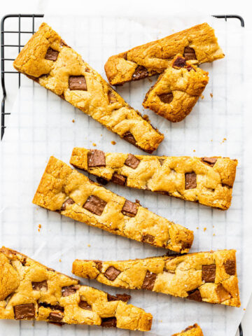 Wedges of blondie bars with chunks of chocolate on a cooling rack.