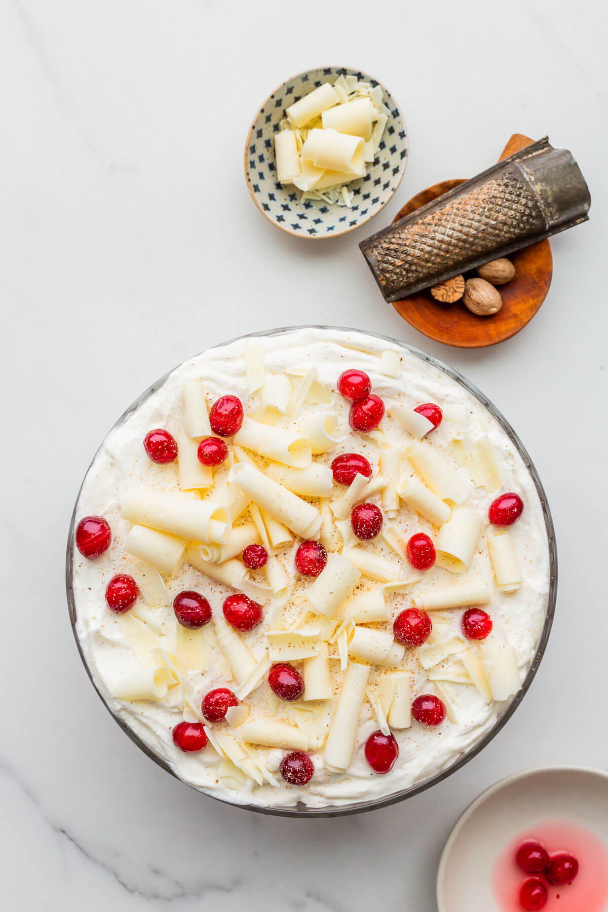 White chocolate curls, cranberries and grated nutmeg garnish the top of a Christmas trifle.