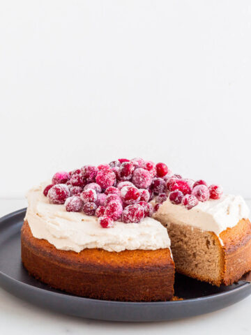 Slicing and serving chestnut cake topped with chestnut cream and sugared cranberries.