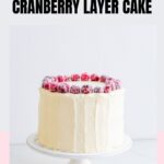 A white chocolate cranberry layer cake on a cake stand.