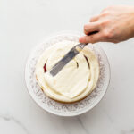 Smoothing frosting on a layer of cake with a mini offset spatula.
