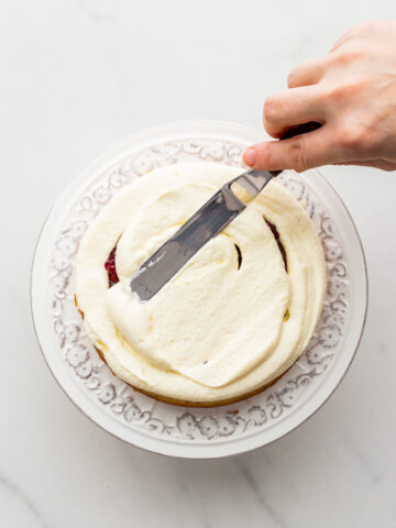 Smoothing frosting on a layer of cake with a mini offset spatula.