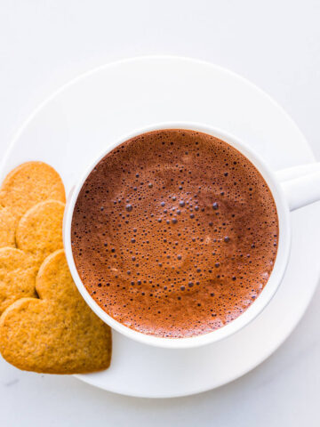 A cup of hot chocolate with cookies.