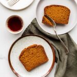 Slices of pumpkin bread served on dessert plates with a cup of coffee.