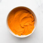 A bowl of smooth, cooked sweet potato purée ready for baking.