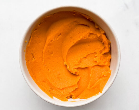 A bowl of smooth, cooked sweet potato purée ready for baking.