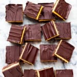 Nanaimo bars cut into squares and served on a marble surface.