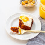 A piece of gingerbread cake with cream cheese frosting and lemon curd served on a dessert plate.