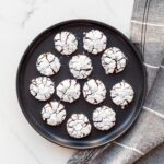 Chocolate crackle cookies arranged on a black plate.