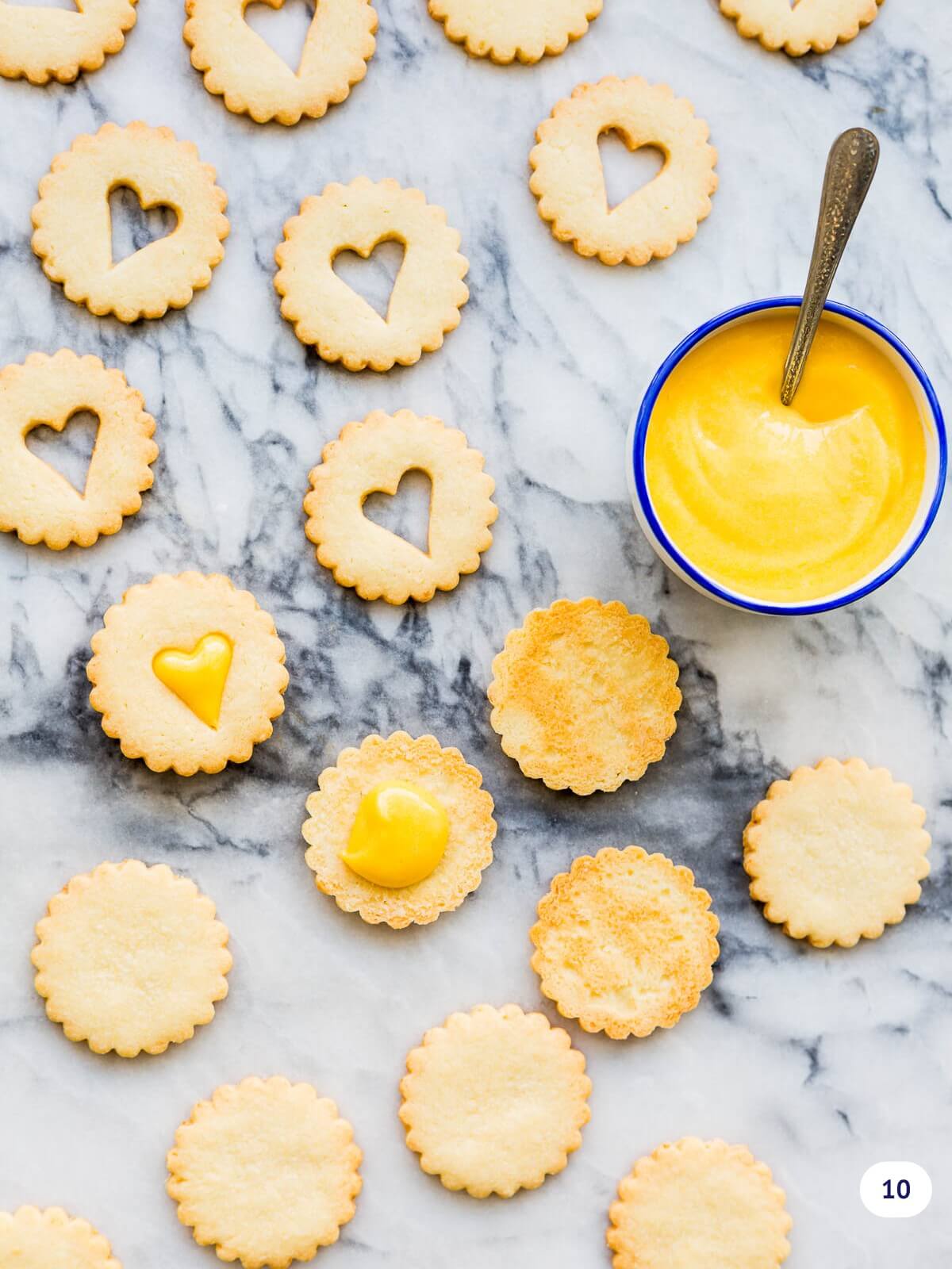 Topping coconut shortbread cookies with lemon curd before sandwiching them together.