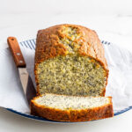 Slicing an orange cake with poppy seeds to serve it.