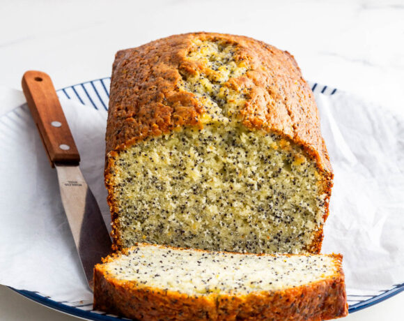 Slicing an orange cake with poppy seeds to serve it.