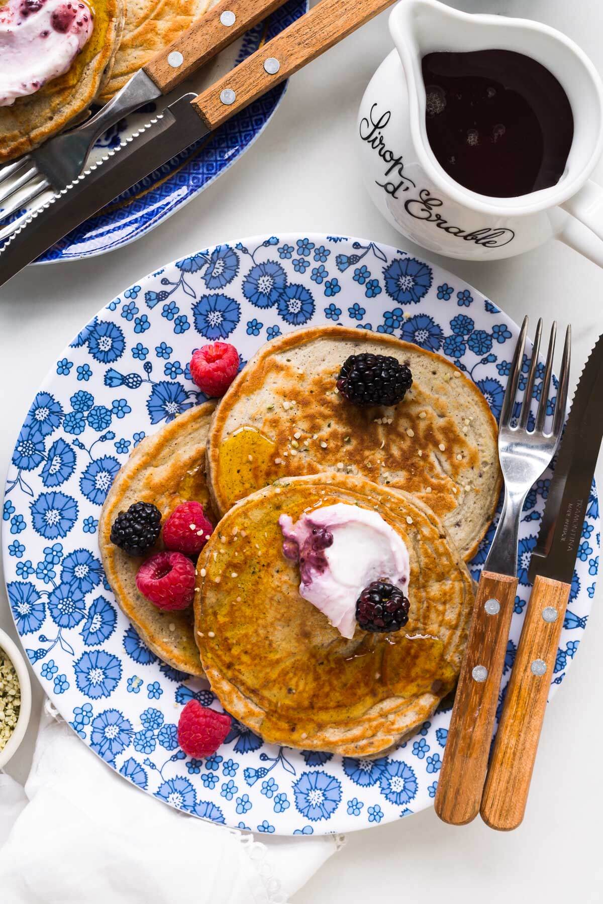 A plate of pancakes served with maple syrup and berries.