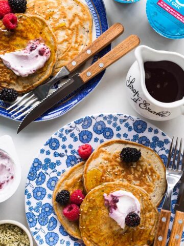 A plate of pancakes with maple syrup, berries and Greek yogurt.