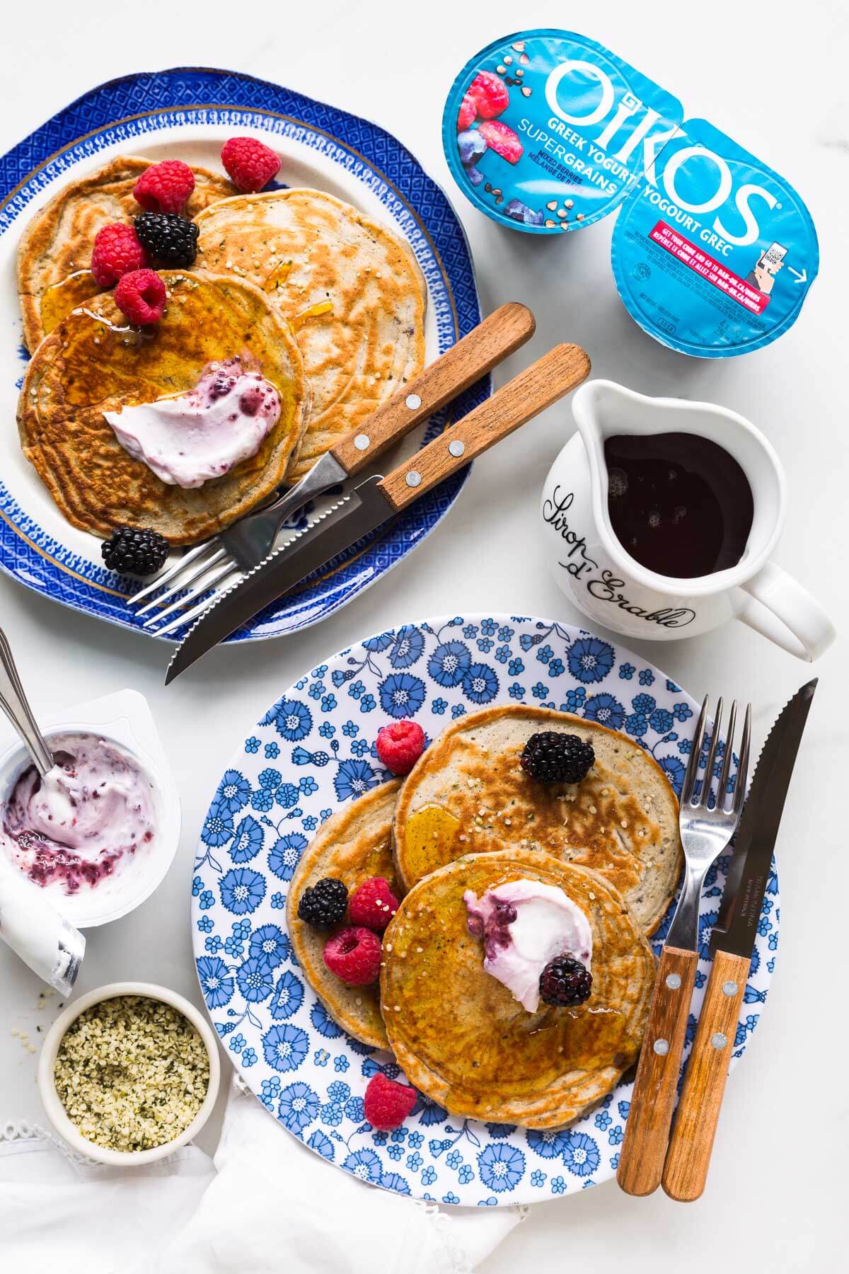 A plate of pancakes served with maple syrup, berries, and greek yogurt.