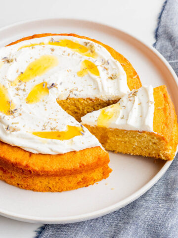 Slicing and serving a honey cake with whipped cream and lavender on top.